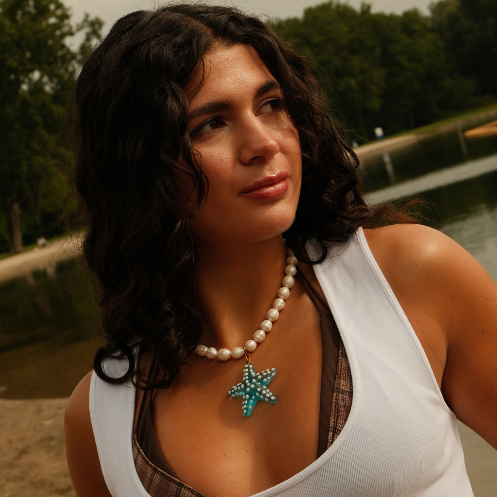 Ocean Star Pendant styled in a coastal summer setting, featuring a turquoise glass starfish with playful white details