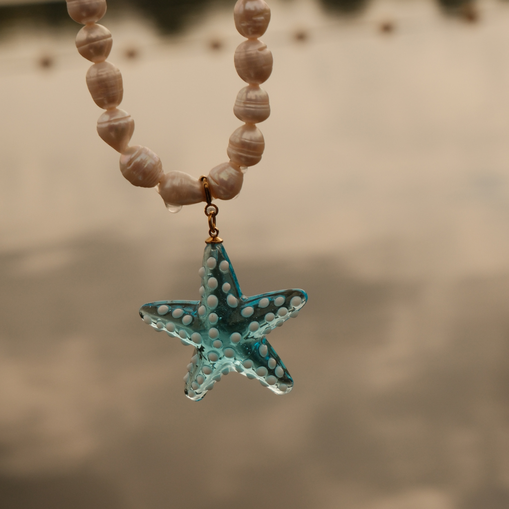 Handmade turquoise starfish pendant in glass with white dot details and an 18K gold-plated finish