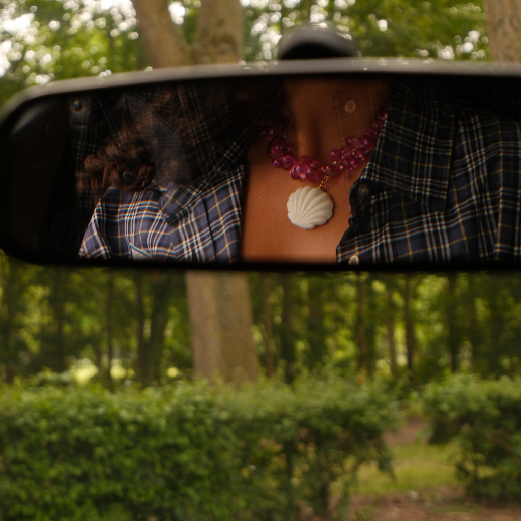 Mermaid 2.0 Pendant reflected in a car's rear-view mirror, featuring a handmade white glass shell.